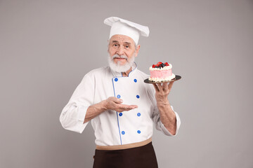 Professional pastry chef with delicious cake on grey background