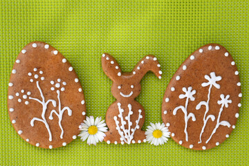 Romantic decorated Easter gingerbread cookies in a shape of egg and bunny, with daisy flowers, green background