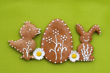 Romantic decorated Easter gingerbread cookies in a shape of chicken, egg and bunny, with daisy flowers, green background