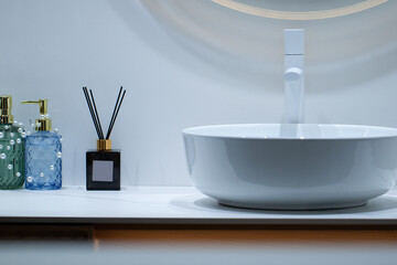 white round sink with washbasin and glass jars with perfumes