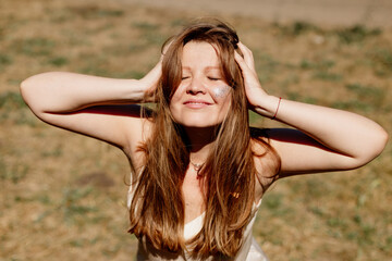 Fototapeta premium portrait of a young woman with long brown hair enjoying the summer sun, meditating