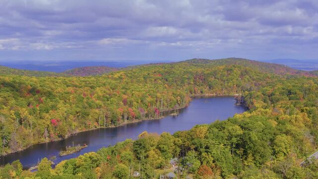 This 4K footage features Canopus Lake with autumn trees beside the lake, bathed in sunlight under cloudy weather, creating a peaceful autumn landscape.