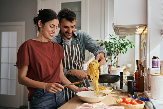 Happy couple cooking pasta in the kitchen.