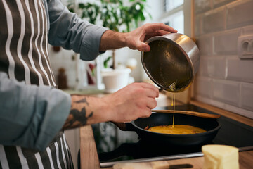 Close up of man preparing scrambled eggs in the kitchen.