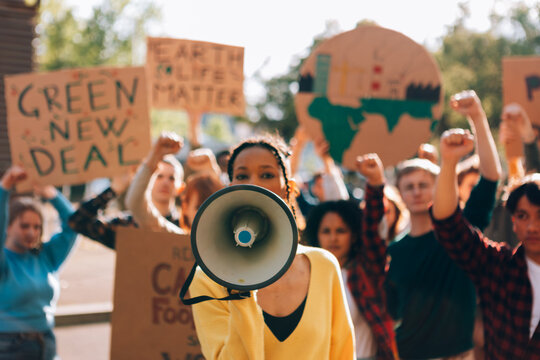 Young activist leading protest using megaphone for climate change and green new deal