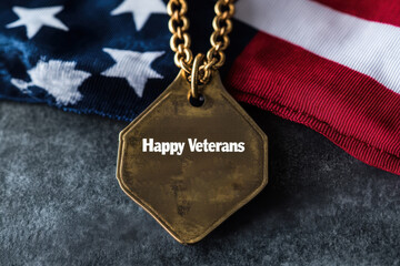 A close up of a gold dog tag with happy veterans day text on a flag background for remembrance day