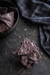 Dark nachos chips on black table.