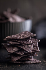 Dark nachos chips on black table.