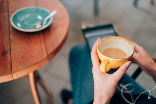 Personal perspective view of a Woman sitting outdoors drinking a cup of coffee using a digital tablet