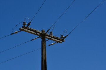 An electric pole of the power distribution network on a blue sky background	