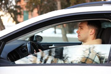 Driver behind steering wheel of modern car, view from outside