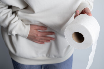 Woman in pain, hand holding belly, stomach and toilet paper roll, girl having stomach ache and...