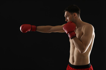 Man in boxing gloves fighting on black background