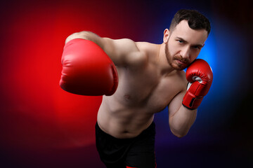 Man with boxing gloves fighting on dark background in neon lights