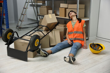Accident at work. Unconscious woman and overturned hand truck on floor in warehouse