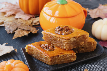 Delicious Baklava Adorned With Walnuts Served on a Black Plate With Decorative Pumpkins