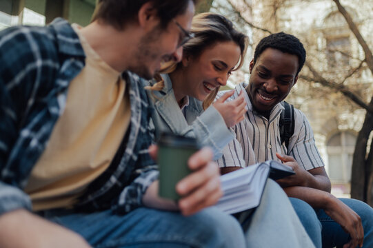 University students laughing together while studying outdoors