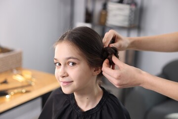 Fototapeta premium Hairdresser doing girl's hairstyle in salon, closeup