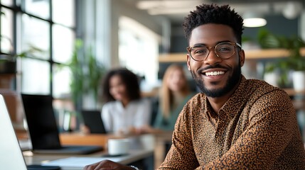 Portrait of a smiling black man with glasses in an office with coworkers in the background