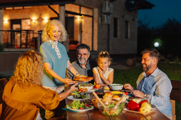 Family enjoying evening meal together in the garden of their house