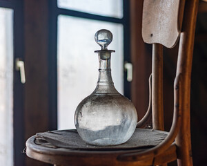 Old Vintage Glass Decanter on a wooden chair. Antique Object.