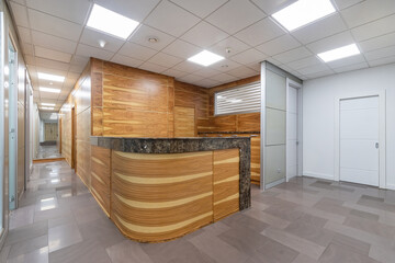 Bright lobby of a modern office. The information desk is decorated with light wood panels..