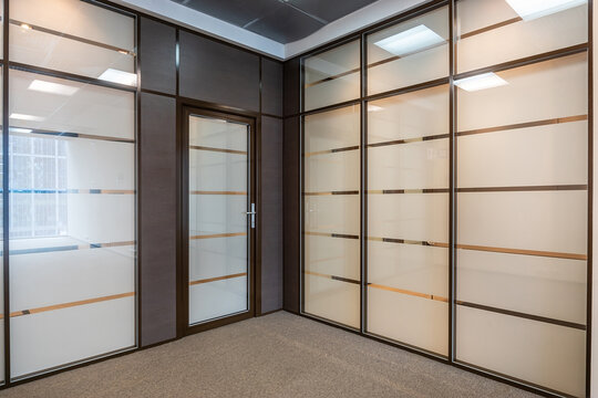 The empty space of a small modern office. The walls are decorated with dark wood panels..