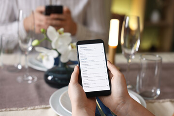 Couple choosing dishes from digital menu at restaurant, closeup