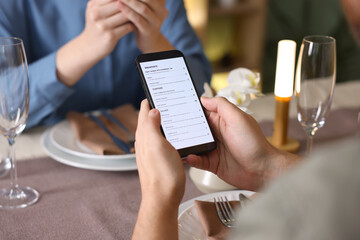Couple choosing dishes from digital menu at restaurant, closeup