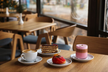 Aromatic coffee and delicious desserts served on wooden table in cafe