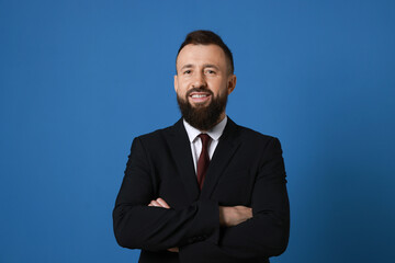 Handsome bearded man in suit on blue background