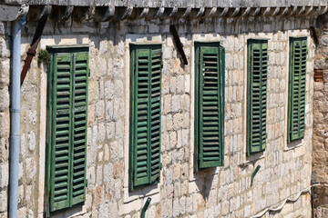 Rustic Stone Wall with Green Wooden Shutters in Traditional Mediterranean Style