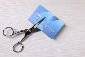 Credit card and scissors on white wooden table, top view