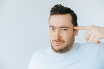 Man gestures at his head with a questioning expression in indoor setting