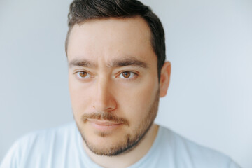 Obraz premium Focused man with brown eyes and light shirt in neutral background