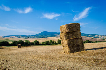 Quattro balle di fieno accatastate in un campo della Val d'Orcia dopo la mietitura in una giornata estiva di sole