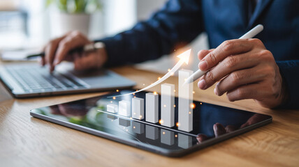 Person using a tablet and laptop with a rising bar graph and arrow overlay showing growth trend