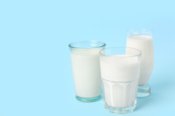 Glasses of milk on light blue background