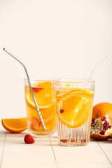Glasses of infused water with orange slices on white tile table