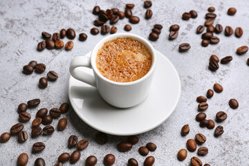 Cup of hot espresso and coffee beans on grey grunge background