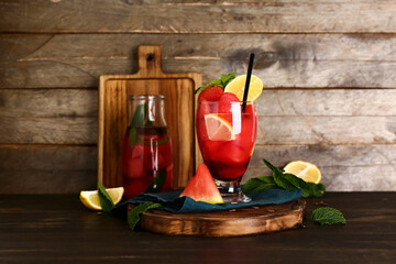 Glass and bottle of fresh watermelon lemonade and mint on wooden background