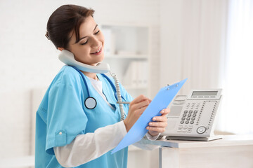 Female medical intern talking by telephone in clinic