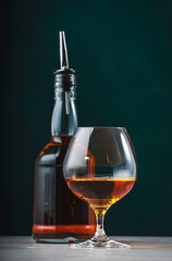 French cognac V.S.O.P. in snifter glass with bottle on dark green background