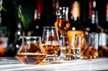 French Brandy in glass with bottle on dark green background, hard light