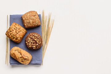 Napkin with delicious buns and wheat ears on white background