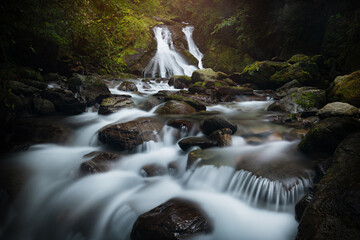 Stunning waterfall in Adjara, Georgia, flowing over moss-covered rocks in a lush green forest. The long exposure effect creates a smooth, silky look to the water.
