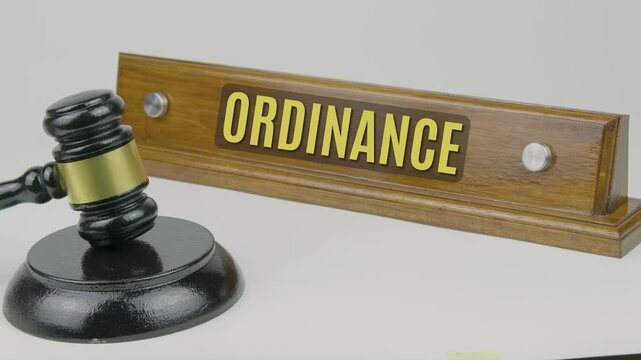 "Ordinance" text on a nameplate beside a gavel, symbolizing a law or regulation enacted by a local government or authority to address specific issues within a jurisdiction