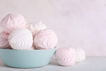 Bowl with tasty marshmallows on table against white background