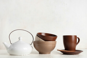 Stack of brown clean tableware and teapot on white background