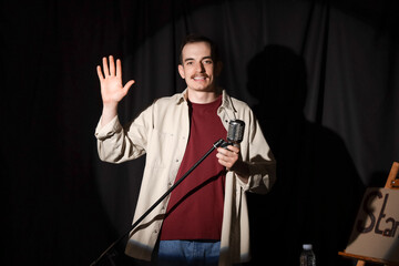 Standup comedian waving hand on stage